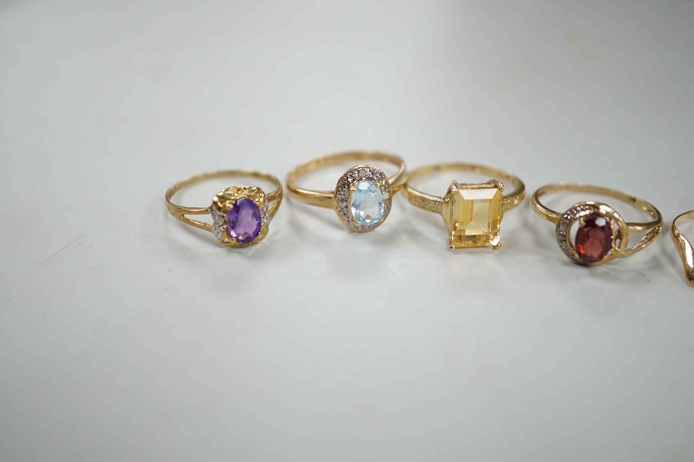 Five assorted modern 375 and gem set rings including amethyst and citrine, together with a 9ct wishbone shaped ring, gross weight 7.6 grams.